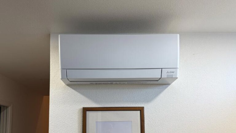 Sleek white Mitsubishi Electric ductless mini-split air conditioner mounted neatly on a modern white wall.