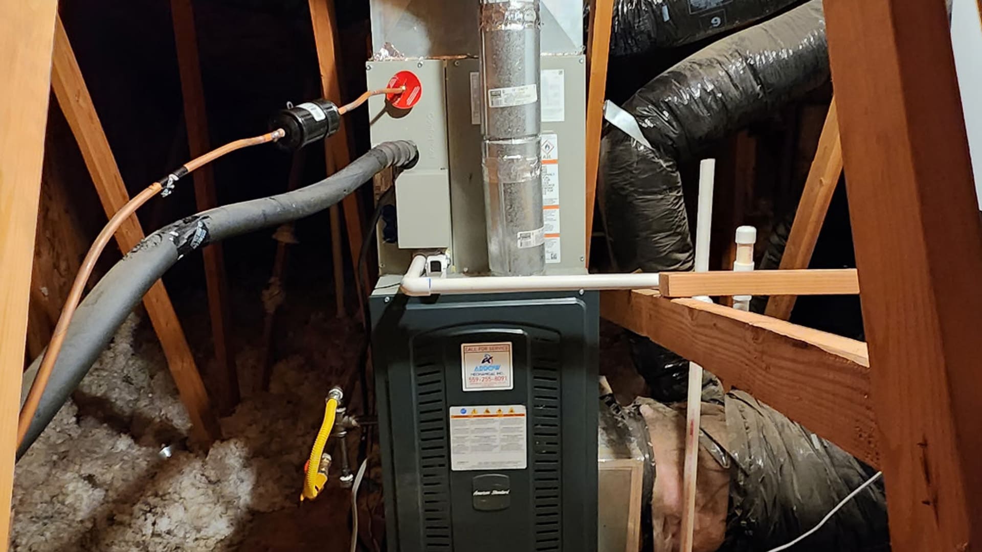 An American Standard HVAC furnace and coil system installed in a residential attic with flexible ductwork by Arrow HVAC.